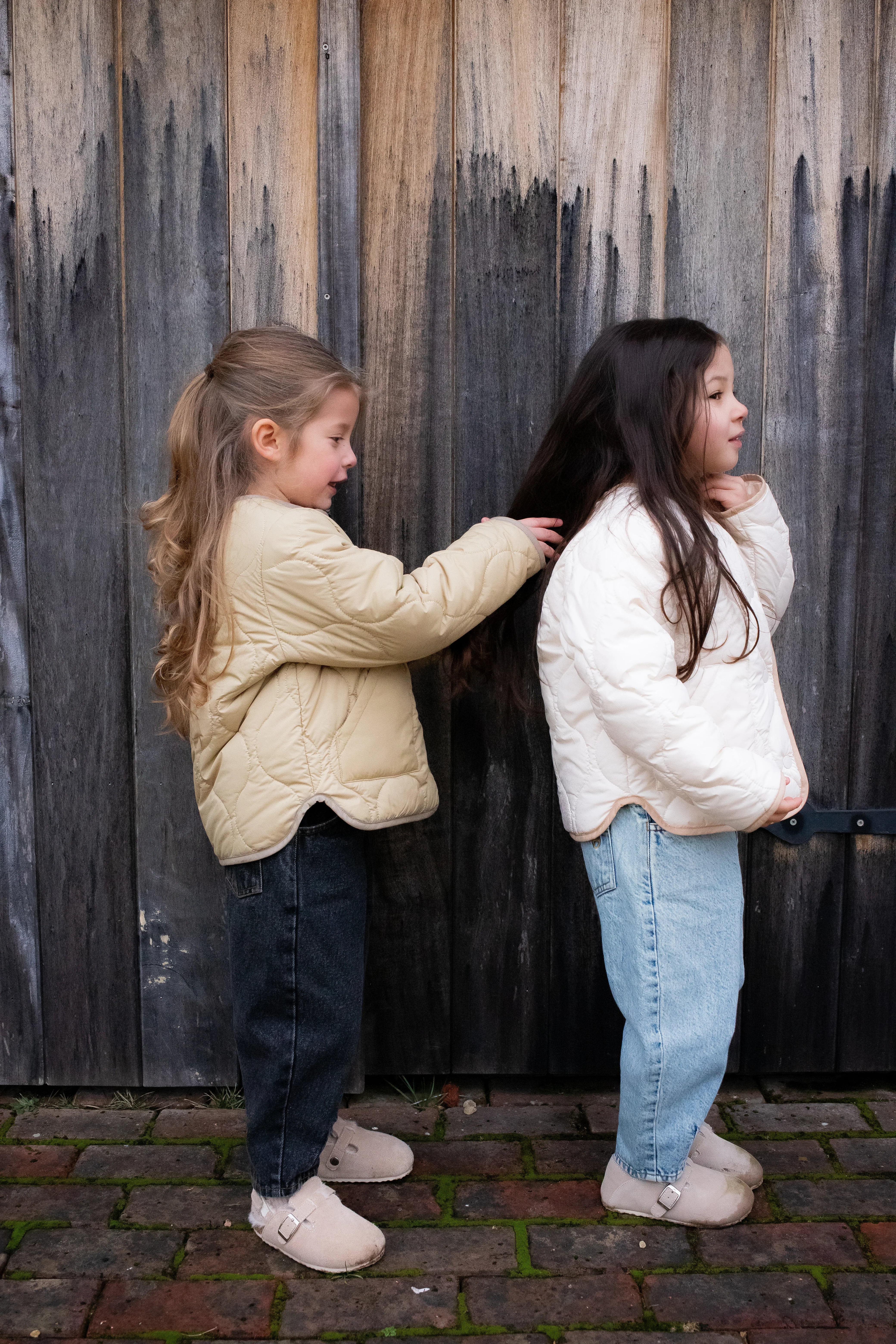 young-girls-cream-jackets-wooden-wall